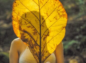 woman in white tank top holding yellow maple leaf