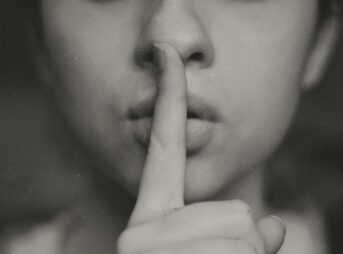 grayscale photo of woman doing silent hand sign