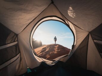 a man standing in a tent looking out into the distance