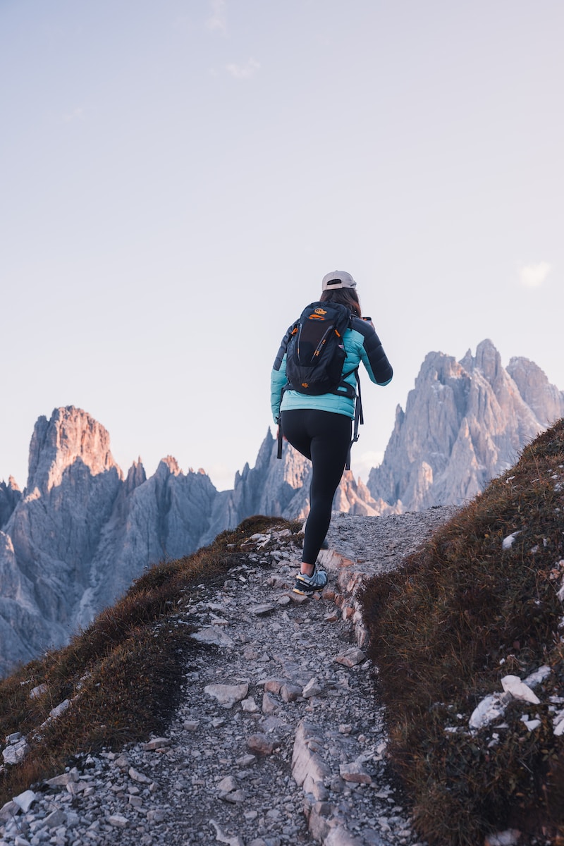 a woman hiking up a rocky trail in the mountains