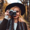 a woman wearing a hat and scarf holding a camera