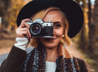 a woman wearing a hat and scarf holding a camera
